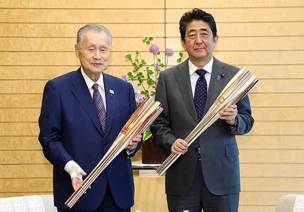 Os ex-primeiros ministros do Japo Yoshiro Mori e Shinzo Abe seguram dois modelos da tocha olmpica utilizadas nos Jogos Olmpicos de Tquio 2020 (Tquio 2021). Foto: kantei.go.jp