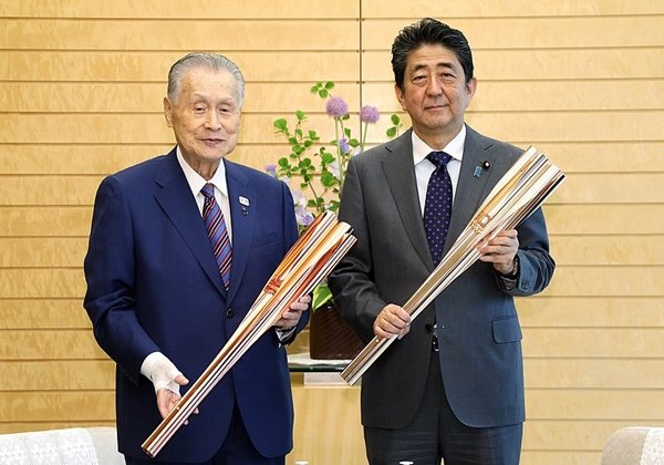 Os ex-primeiros ministros do Japão Yoshiro Mori e Shinzo Abe seguram dois modelos da tocha olímpica utilizadas nos Jogos Olímpicos de Tóquio 2020 (Tóquio 2021). Foto: kantei.go.jp